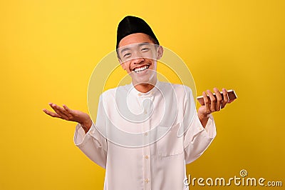 Portrait of relaxed smile young Asian Muslim man stay calm down holding a mobile phone Stock Photo