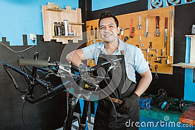 Portrait of a repairman in an apron leaning in a bicycle repair shop Stock Photo