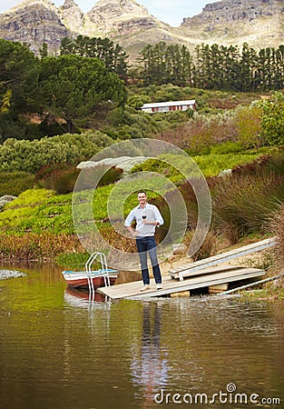 Portrait, river and a man drinking red wine on a pier outdoor in nature on his farm for agriculture. Water, drink and Stock Photo