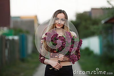 Portrait of a romantic smiling young woman with a bouquet of lilac outdoors shallow depth of field Stock Photo