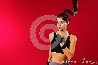 A portrait of a running caucasian girl in a top with long hair in a wave over her head looks to the side on a red Stock Photo