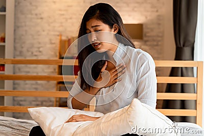 Portrait of 20s young Asian woman having difficulty breathing in bedroom at night. Shortness of breath, asthma Stock Photo