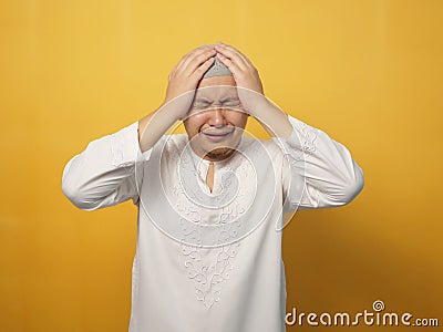 Portrait of sad Asian muslim man crying against yellow background, sadness depression hopeless Stock Photo