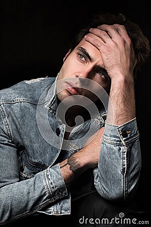 Portrait of a sad, brooding young man on black background Stock Photo