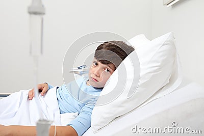 Portrait of sad child looking at camera lying in bed in hospital room on white background with copy space Stock Photo