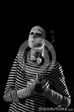 Portrait of sad crying mime on black background. Portrait of a male mime artist standing under umbrella expressing sadness and lon Stock Photo