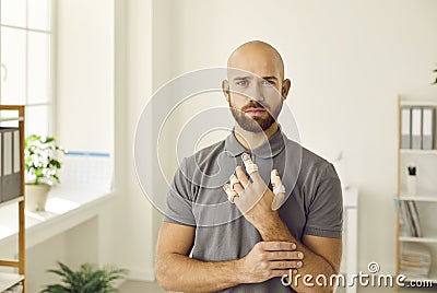 Portrait of sad man who has hurt his fingers and is now wearing adjustable finger splint braces. Stock Photo