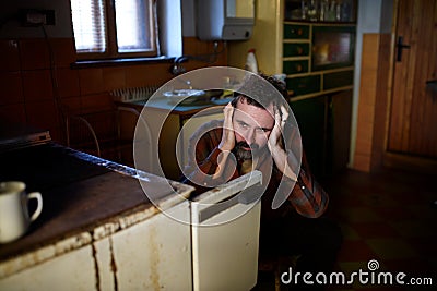 Portrait of sad poor mature man sitting indoors at home, poverty concept. Stock Photo
