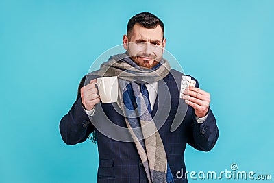 Portrait of sad sick business wearing official style suit and wrapped in scarf, treating with pills Stock Photo
