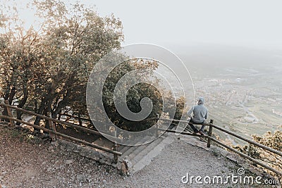 Portrait of a Sad or unhappy man sitting on a railing at Sunset Stock Photo