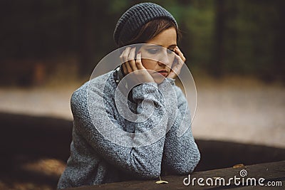 Portrait of sad woman sitting alone in the forest. Solitude concept. Millenial dealing with problems and emotions. Stock Photo