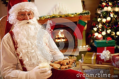 Portrait Santa Claus sitting and enjoying in cookies and milk Stock Photo