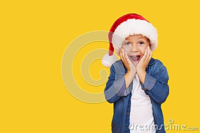 Portrait of a satisfied little child boy in christmas Santa hat. laughing isolated over yellow background. Stock Photo