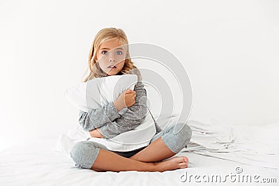 Portrait of a scared little girl hugging pillow Stock Photo