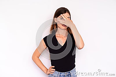 Portrait of scared young woman peeking through fingers Stock Photo