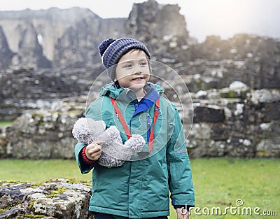 Portrait of School kid taking teddy bear explore with his learning history, Happy child boy wearing warm cloths holding his soft Stock Photo