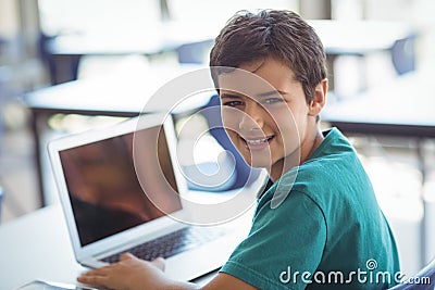 Portrait of schoolboy using laptop in classroom Stock Photo