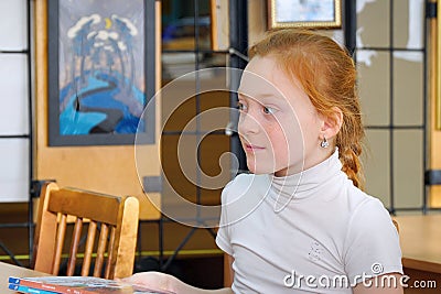 Portrait of a schoolgirl with red hair sitting at a Desk Editorial Stock Photo