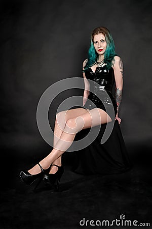 A portrait of a seductive young beautiful woman with green hair wearing latex clothe isolated Stock Photo