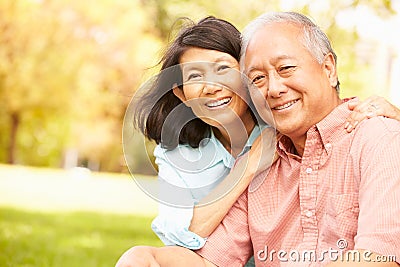 Portrait Of Senior Asian Couple Sitting In Park Together Stock Photo