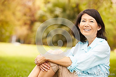 Portrait Of Senior Asian Woman Sitting In Park Stock Photo