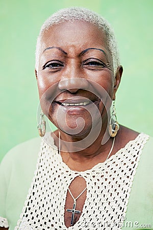 Portrait of senior black woman smiling at camera on green background Stock Photo