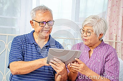 Portrait of senior couple feeling concerned using electronic tablet at the bed room Stock Photo