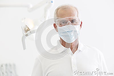 Portrait of senior dentist wearing mask and glasses at dental clinic Stock Photo