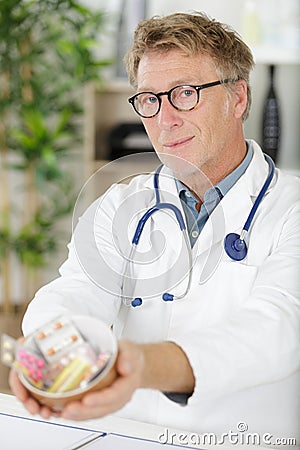 Portrait senior doctor offering bunch pills Stock Photo