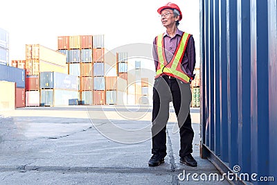 Portrait of senior elderly Asian worker engineer wearing safety vest and helmet, standing at logistic shipping cargo containers Stock Photo