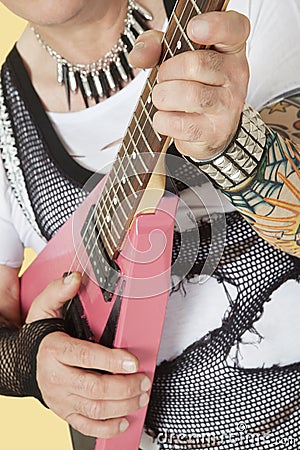 Midsection of senior male punk musician playing guitar Stock Photo