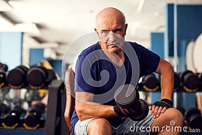 A portrait of senior man in the gym training with dumbbells. People, health and lifestyle concept Stock Photo