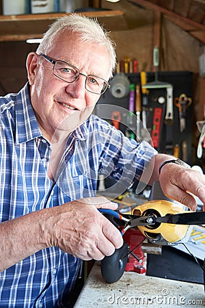 Portrait Of Senior Man Working On Model Radio Controlled Aeroplane In Shed At Home Stock Photo