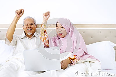 Senior couple lifting hands together on bed Stock Photo