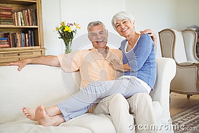 Portrait of senior woman sitting on mans lap in living room Stock Photo