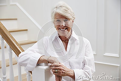 Portrait Of Senior Woman Standing By Staircase At Home Stock Photo