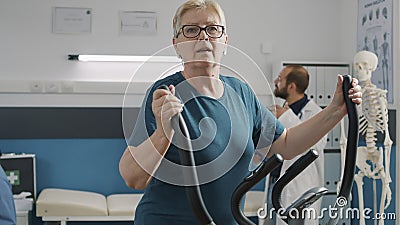 Portrait of senior woman doing physical therapy on stationary bicycle Stock Photo