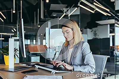 Portrait of a sensible and fair successful woman, businesswoman working in a modern office, at the computer, confident and focused Stock Photo