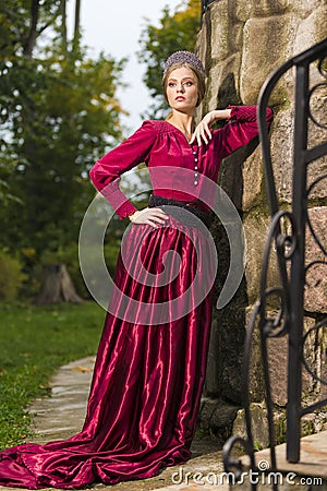 Portrait of Sensual Cute Girl With Tiara Posing with Lifted Hand Near Old Stony Wall Outdoor Stock Photo