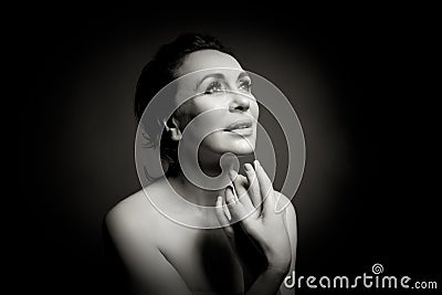 Portrait of a sensual fifty year old woman on grey studio background. Monochrome shot. Stock Photo