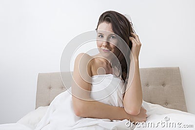 Portrait of sensuous woman covered with bedsheet in bed Stock Photo