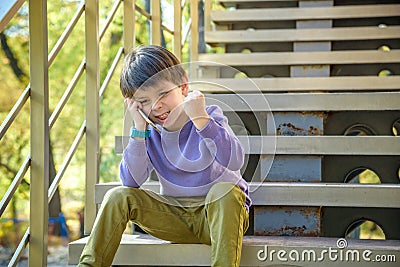 Portrait of a serious angry teenage boy talking on smartphone. Outdoor. Technology, winning, people, children concept Stock Photo