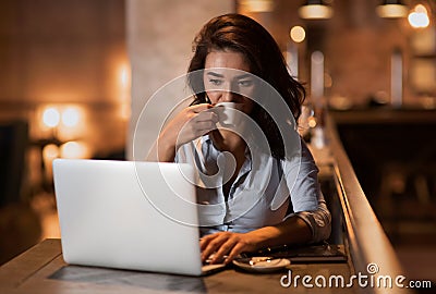 Portrait of serious elegant businesswoman sitting at modern restaurant working on her laptop and drinking coffee Stock Photo