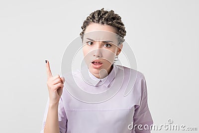 Portrait of serious, frowning, angry, grumpy young woman with african braids pointing finger upwards, scolding someone Stock Photo