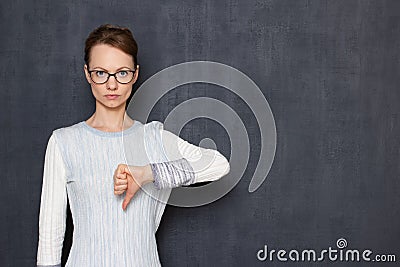 Portrait of serious girl giving thumb down sign of disapproval Stock Photo