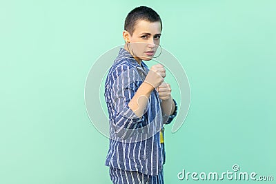 Portrait of serious handsome beautiful short hair young stylish woman in casual striped suit standing with boxing fists and Stock Photo