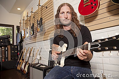 Portrait of serious mid adult man sitting in guitar store Stock Photo