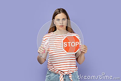 Serious strict bossy woman showing red stop sign and holing plastic bottle in hands. Stock Photo