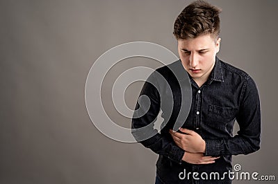 Portrait of serious stylish attractive man dressed with a casual black shirt gesturing stomach ache Stock Photo