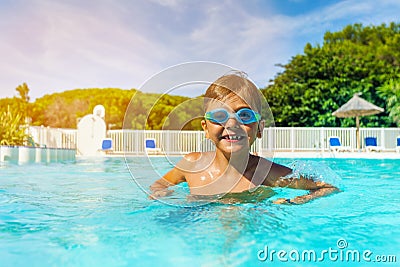 Boy with swimming goggles standing in outdoor pool Stock Photo